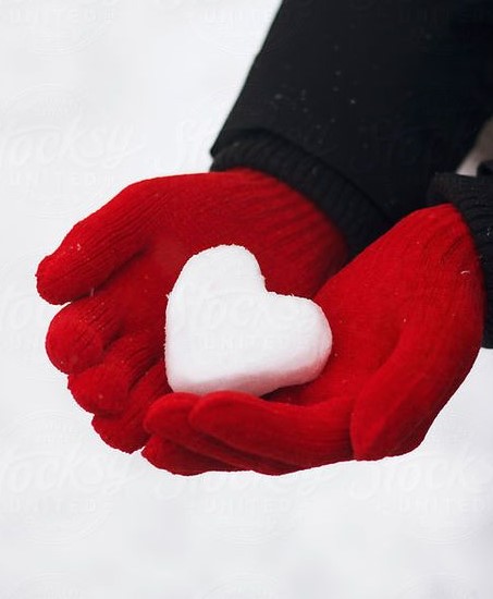 child in red gloves holding a snow heart